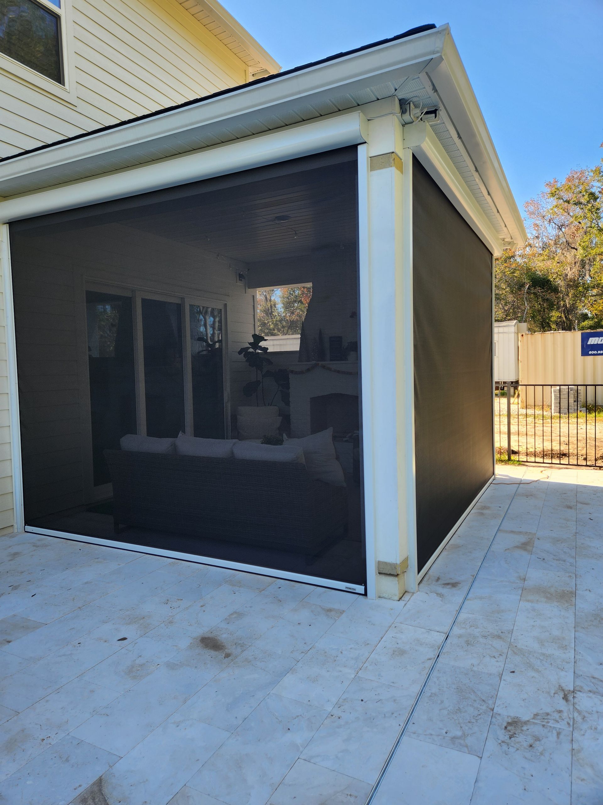 A screened in porch with a couch and a fireplace