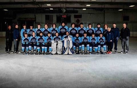 Hockey team poses on ice rink wearing blue jerseys.