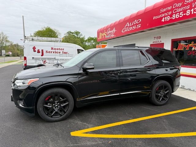 Black SUV parked outside an auto service shop, with yellow parking lines and a red storefront sign.