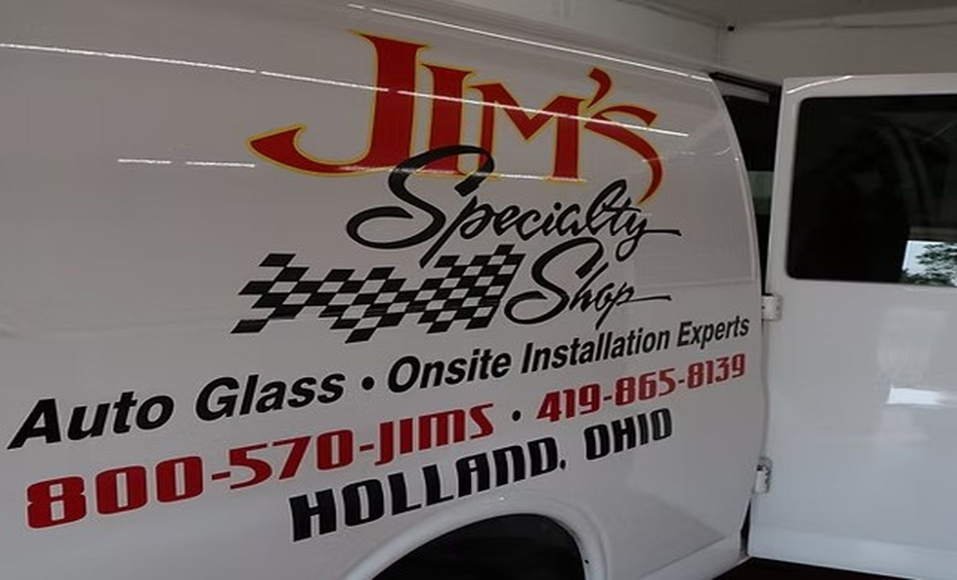 White van with JIM's Specialized Shop auto glass and installation experts logo and contact info.