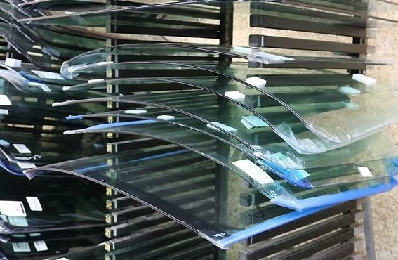 Stacked glass panels on a rack, with a blue-edged sheet in front.