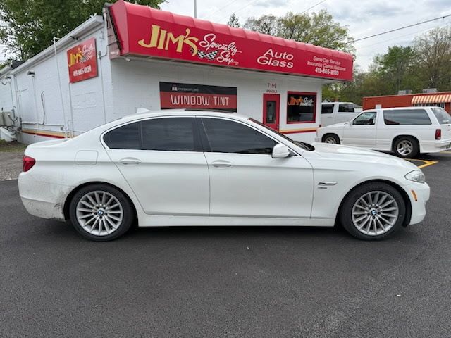 White BMW coupe parked outside Jim’s Auto Sales on a street.