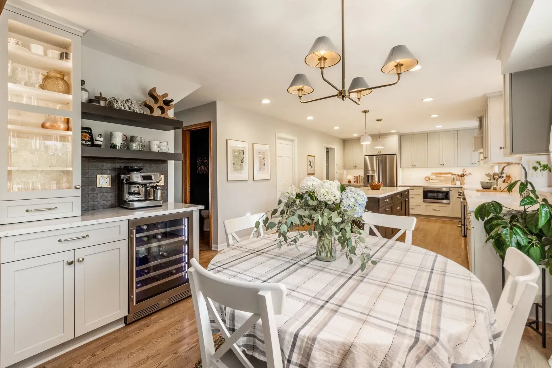 Kitchen with dining table and wine fridge. Light blue walls, white cabinetry, and a wood floor.