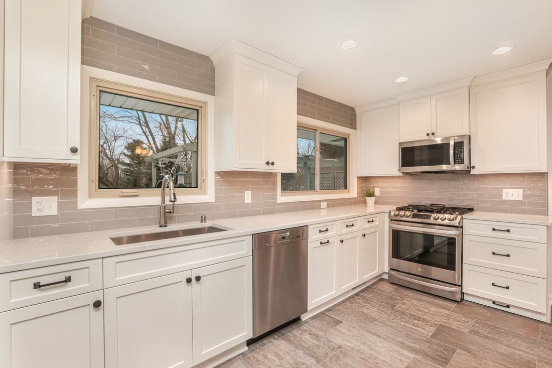 Bright, modern kitchen with white cabinets, stainless steel appliances, and light gray backsplash.