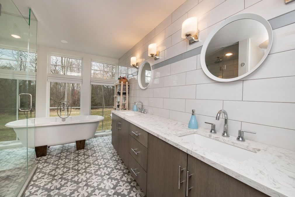 Spacious bathroom with a clawfoot tub, double vanity, patterned tile, and outdoor view.