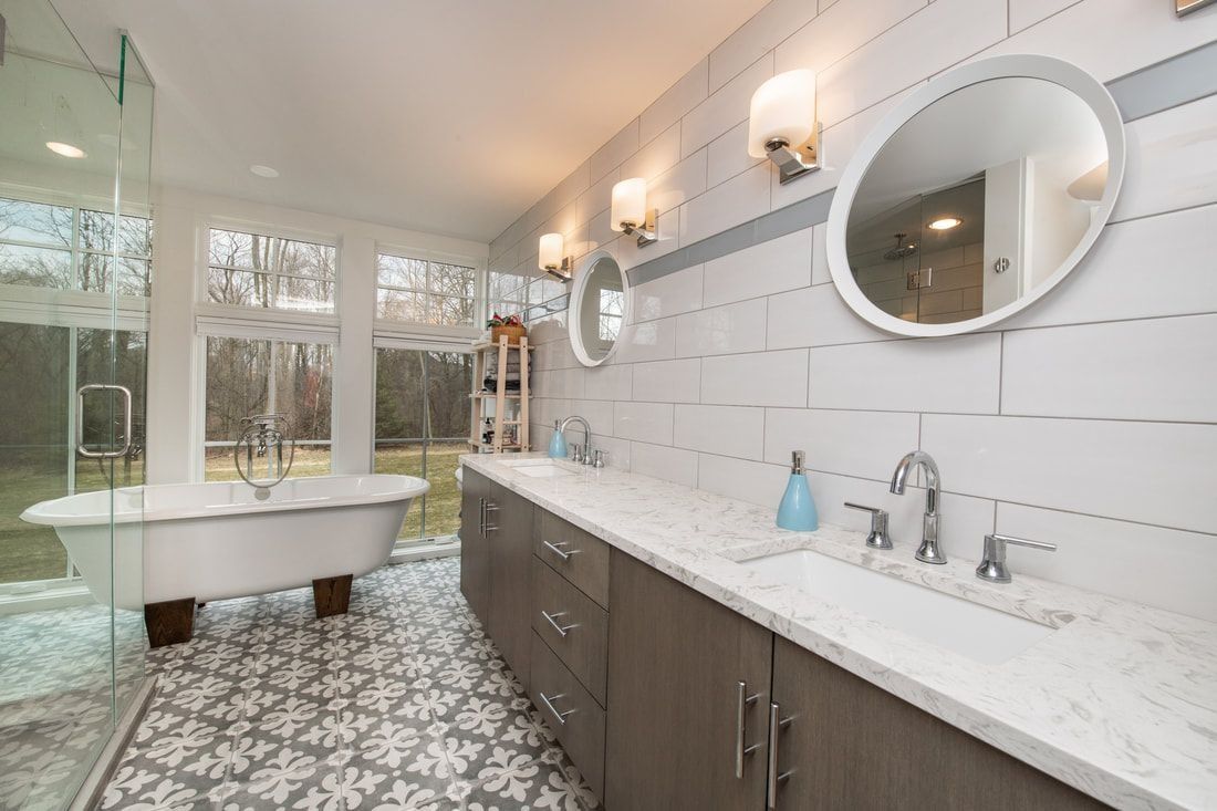 Spacious bathroom with a clawfoot tub, double vanity, patterned tile, and outdoor view.
