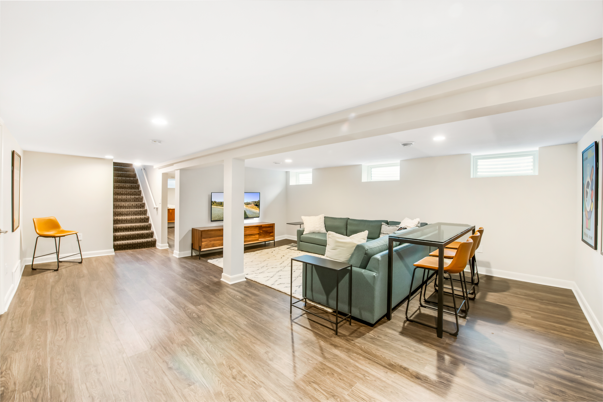 Spacious, finished basement with seating area, bar, and staircase to the upper level.