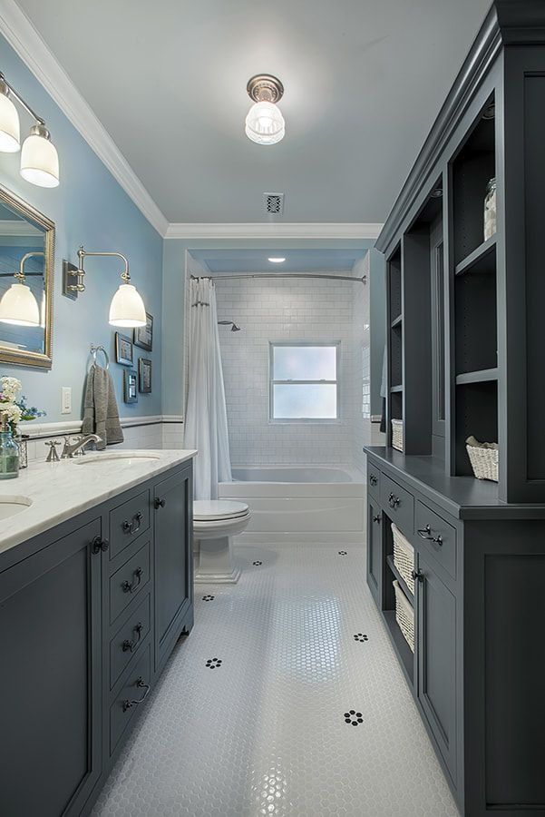 Long, blue and white bathroom with double vanity and built-in shelving.