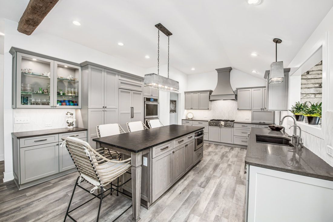 Modern gray kitchen with an island, dark countertops, and light wood-look flooring.