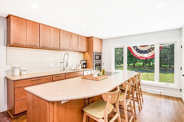 Modern kitchen with wood cabinets, large island with stools, and window with a view.