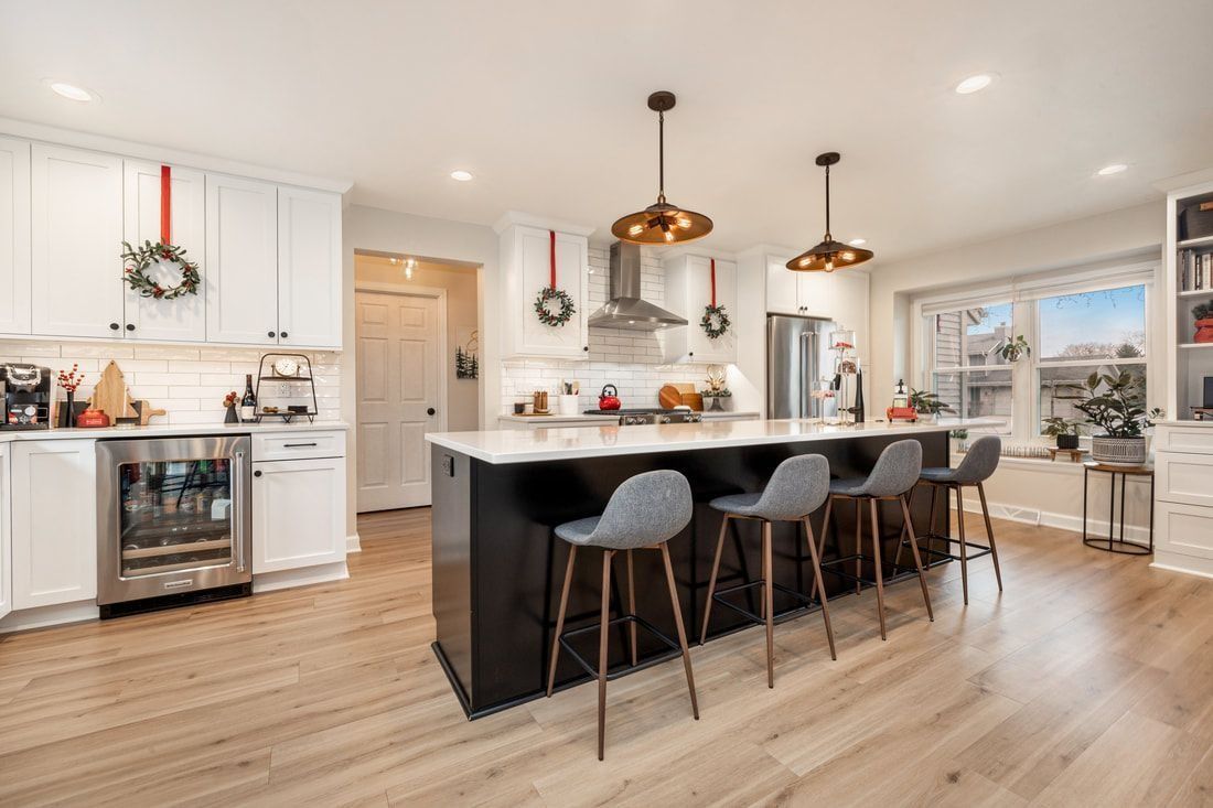 Bright kitchen with white cabinets, dark island, and bar stools.