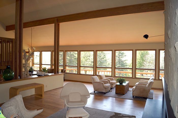 Living room with light wood floors, large windows, and mid-century modern furniture.