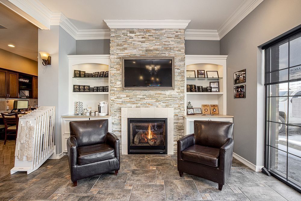 Living room with fireplace, TV, built-in shelves, two leather chairs, and large window.