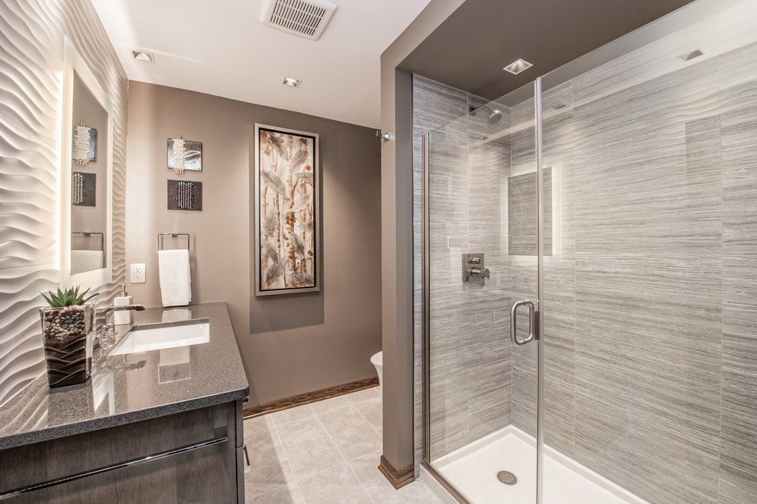 Modern bathroom with a glass shower, gray walls, vanity, and artwork.