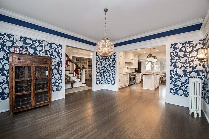 Dining room with floral wallpaper, dark wood floors, and doorways to other rooms.