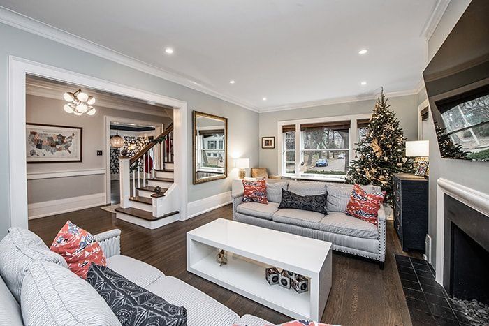 Living room with couches, coffee table, fireplace, Christmas tree, and staircase.