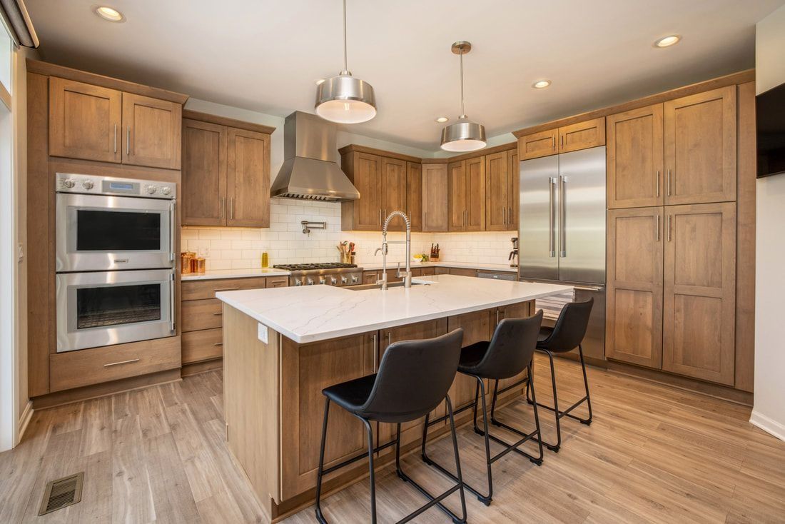 Modern kitchen with wood cabinets, stainless steel appliances, island with stools.
