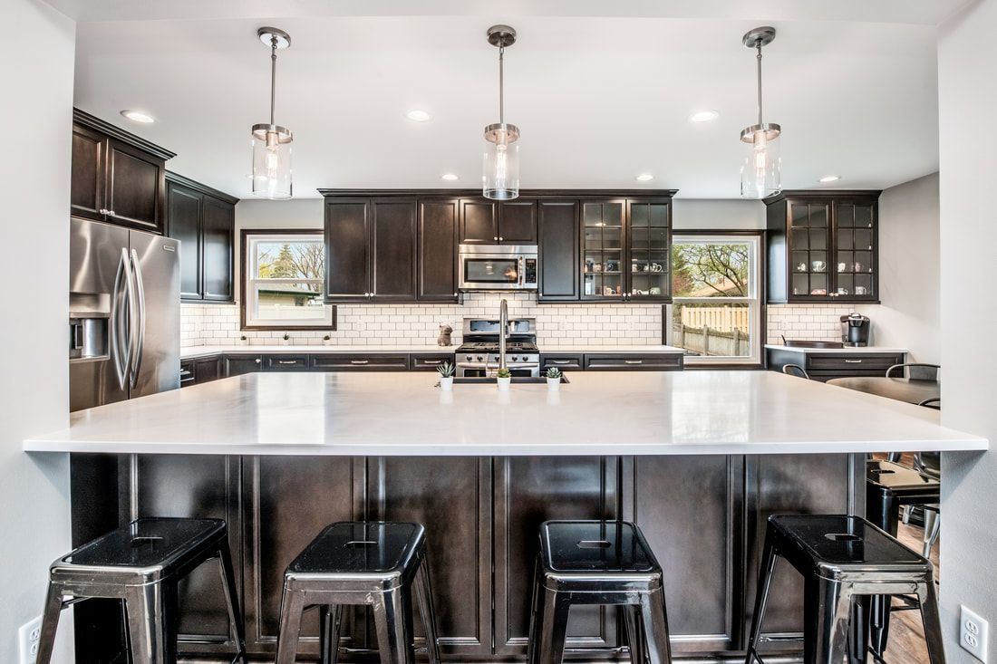 Dark wood kitchen with island and bar stools; stainless steel appliances; pendant lights.