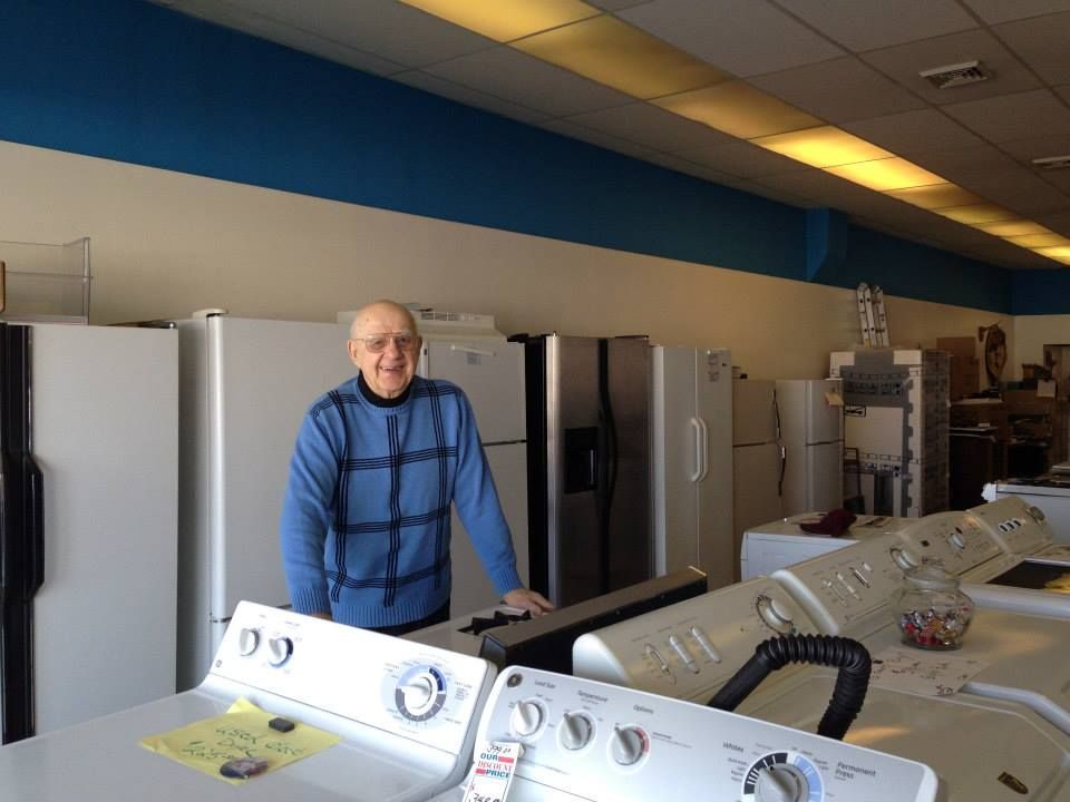 A man is standing in front of a row of appliances in a store.