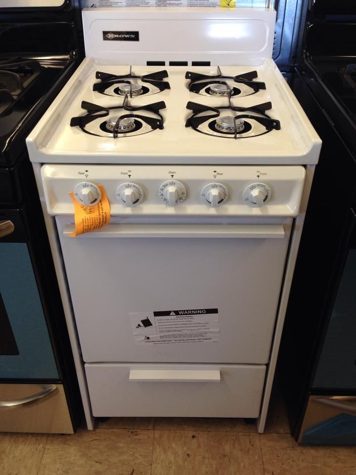 A white gas stove with four burners and a drawer