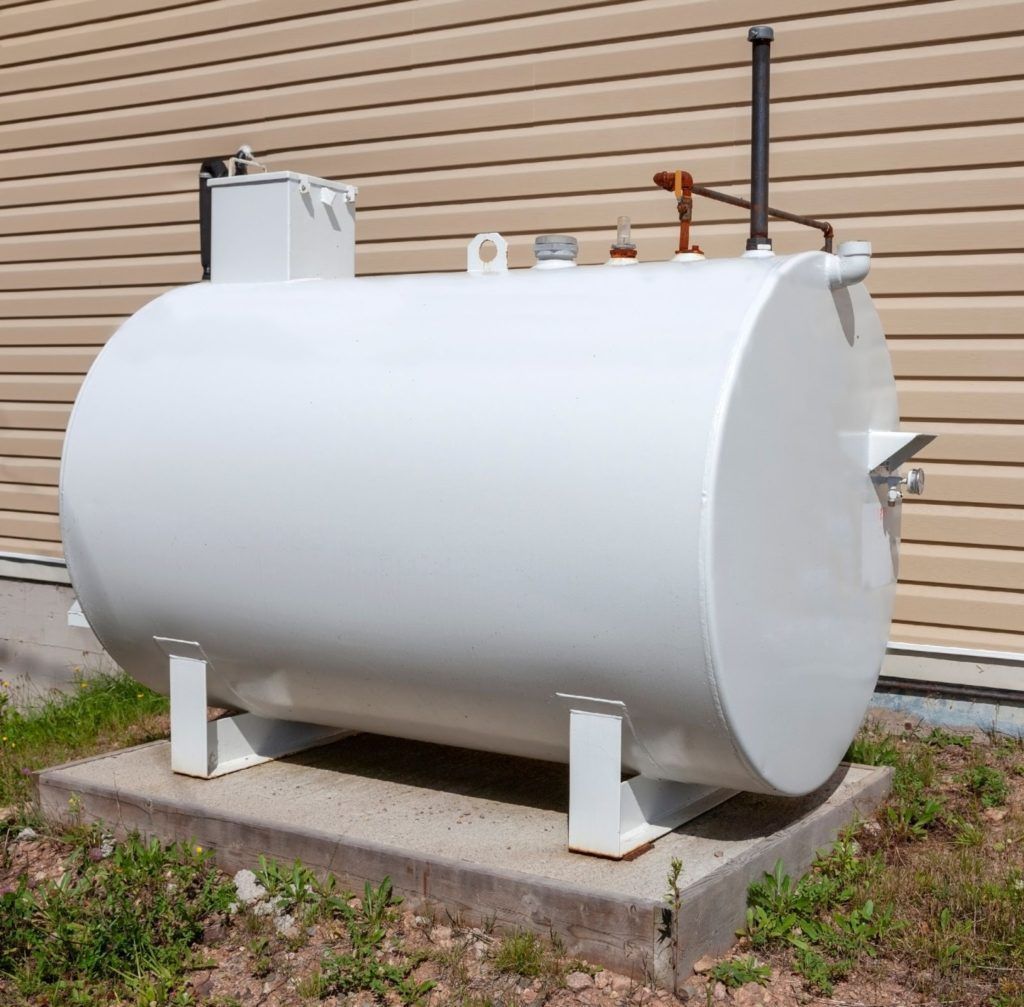White oil tank outdoors, near a building.