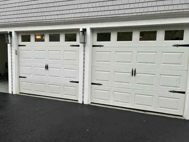 Two white garage doors with black hardware; exterior shot.