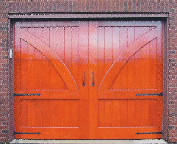 Orange wooden garage doors with black hinges and handles against a brick wall.