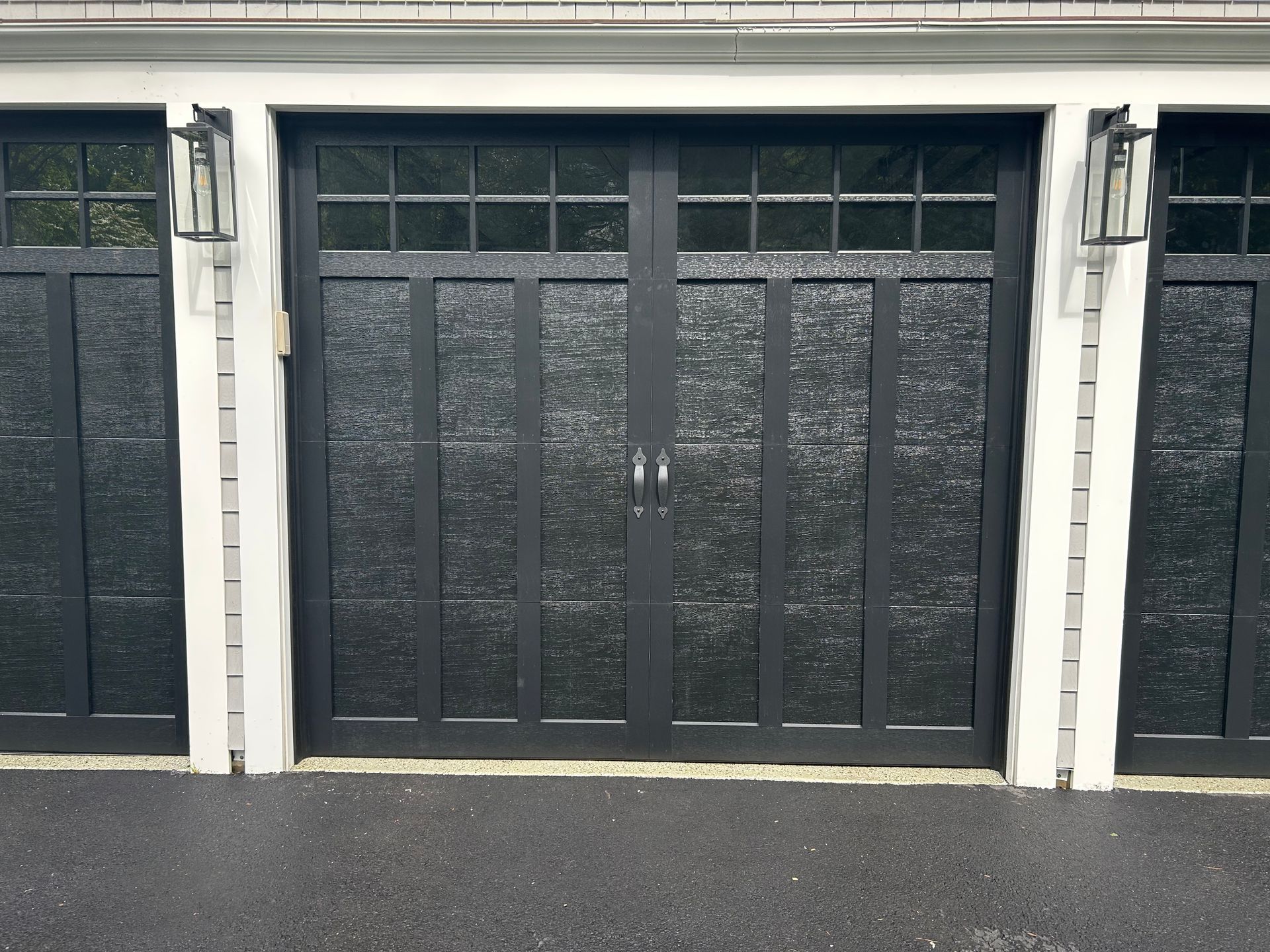 Black garage door with frosted glass panels between two matching doors; outdoor setting.