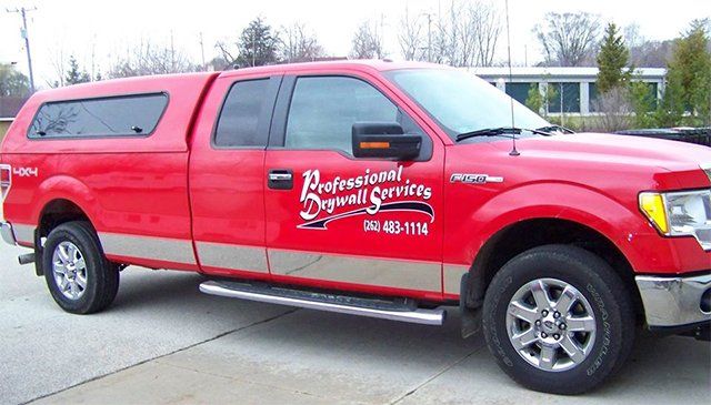 A red truck with professional drywall services written on it