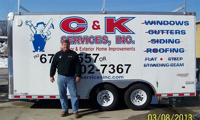 A man stands in front of a trailer that says c & k services inc.