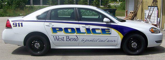 A white police car is parked in front of a building