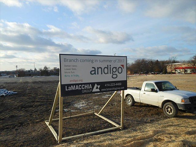 A white truck is parked in front of a sign that says andigo