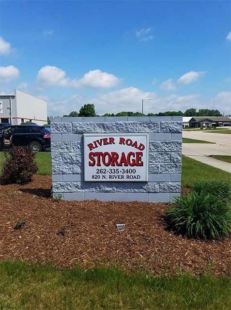 A sign for river road storage is on a brick wall