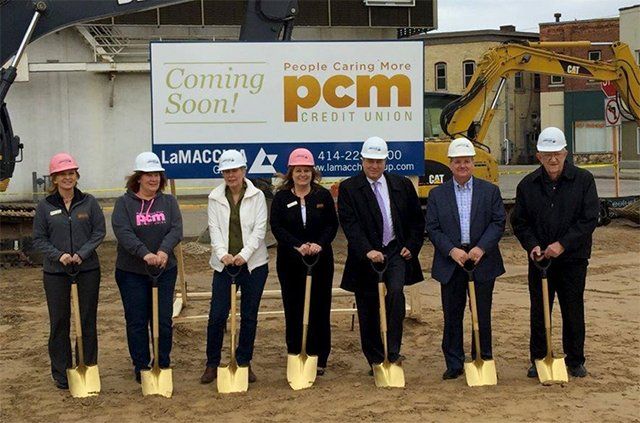 A group of people holding shovels in front of a sign that says coming soon