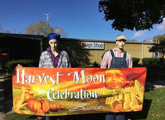 A man and a woman are holding a harvest moon celebration banner