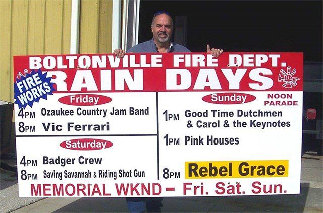 A man holding a sign that says boltonville fire dept rain days