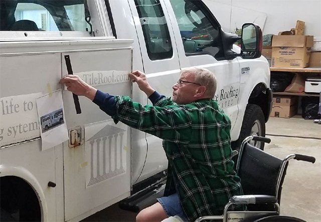 A man in a wheelchair is working on a truck