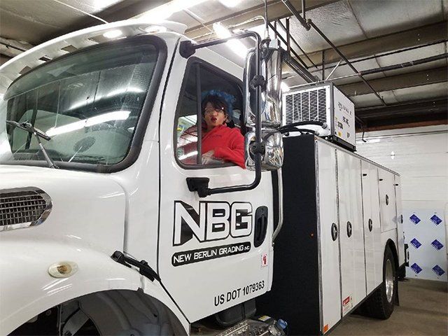 A man is sitting in the driver 's seat of a white truck.