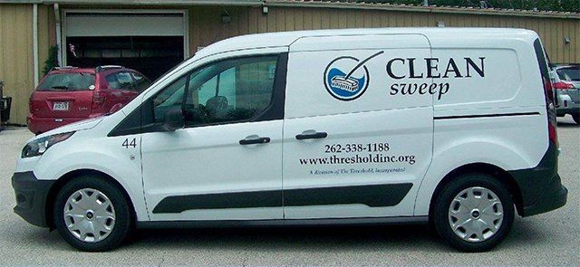 A clean sweep van is parked in front of a building