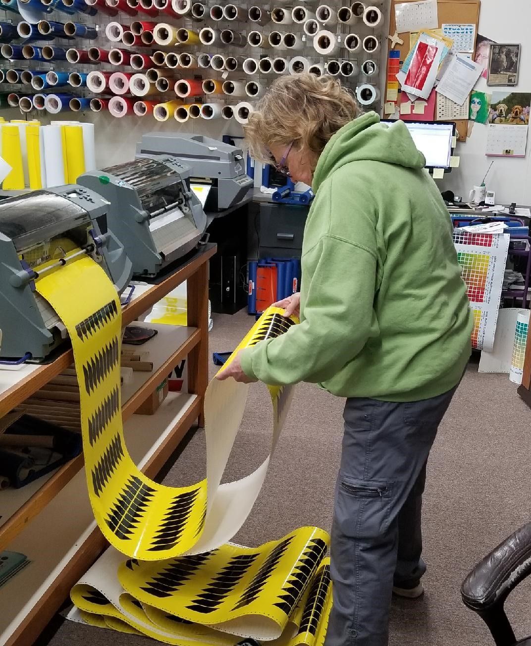 A woman in a green hoodie is working on a roll of yellow tape
