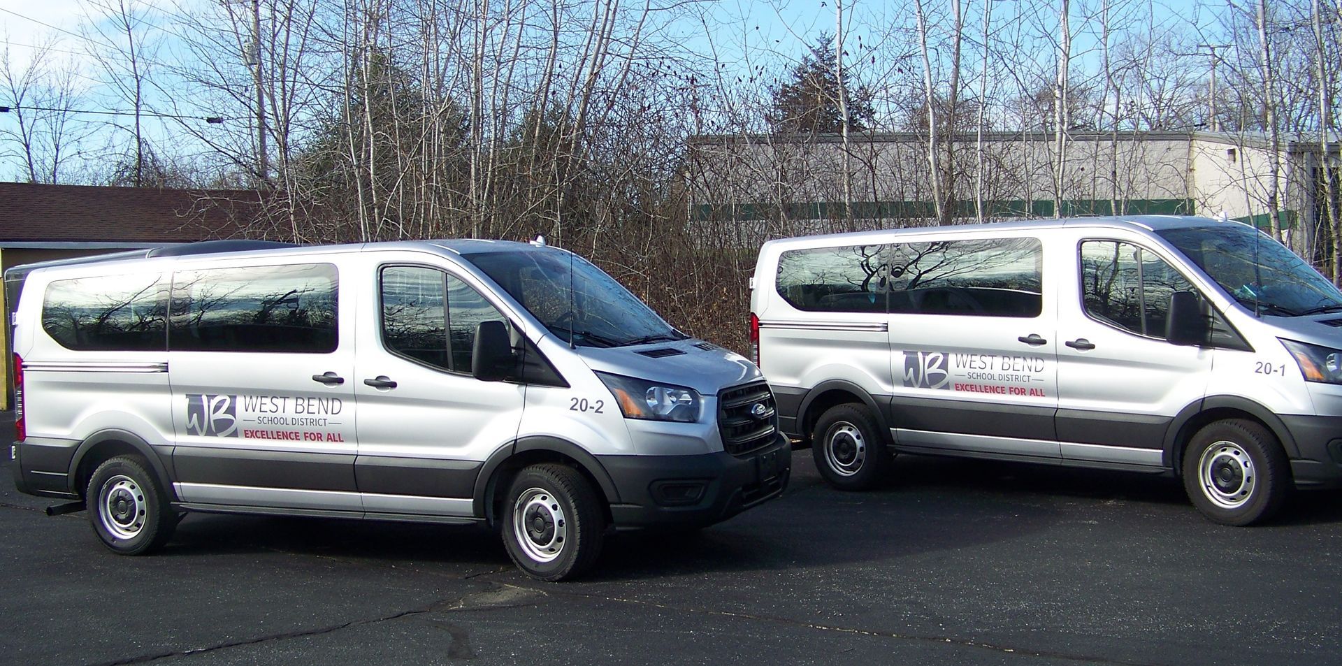 Two white vans are parked next to each other in a parking lot