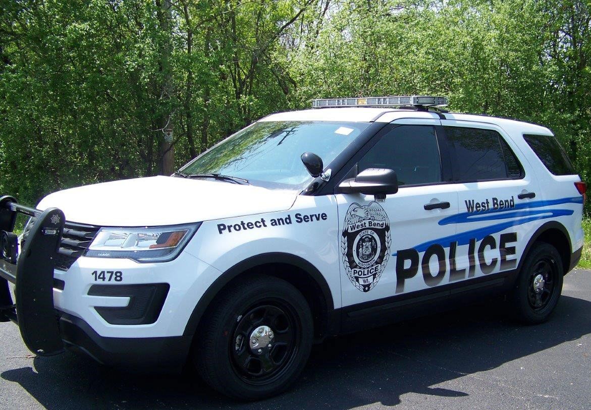 A white police car is parked on the side of the road