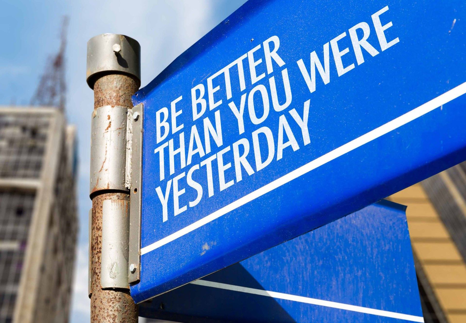Blue street sign with the text Be Better Than You Were Yesterday