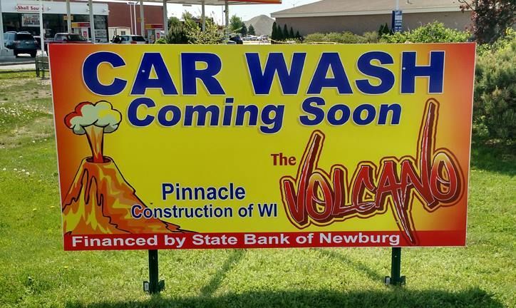 Sign promoting The Volcano car wash, coming soon, with volcano graphic and sponsor info.