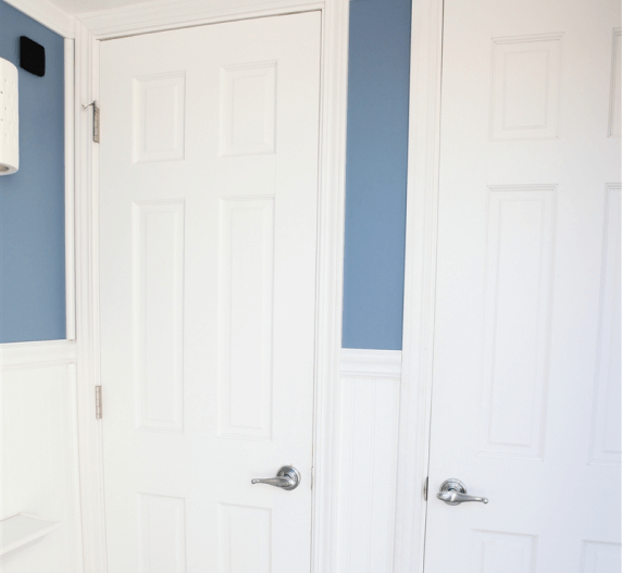 Two white panel doors in a blue and white hallway; chrome door handles are visible.