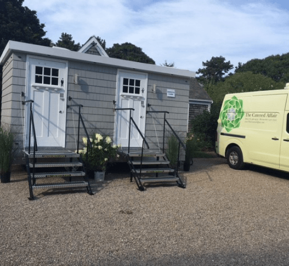 Exterior of two public restrooms with steps, next to a yellow van.
