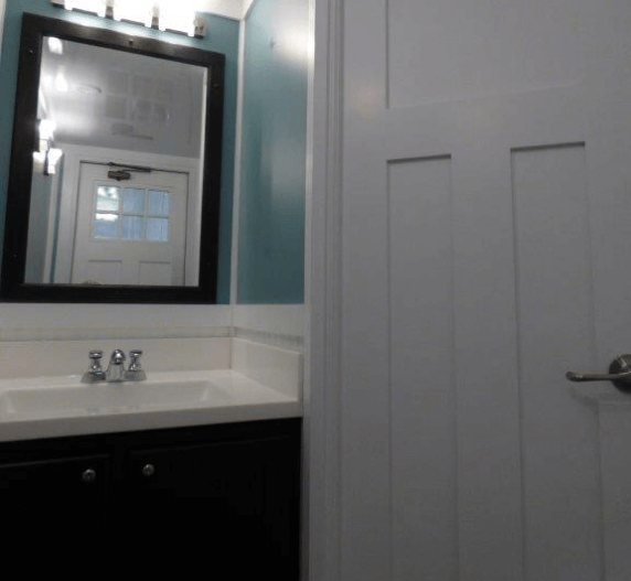 Bathroom with black vanity, white door, and blue wall.