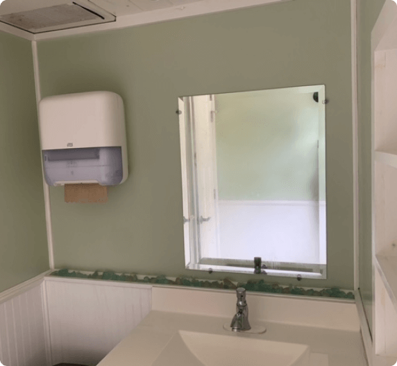 Interior of a restroom with a sink, mirror, and paper towel dispenser.