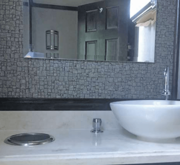 Modern bathroom with a white sink, large mirror, and textured gray wall.