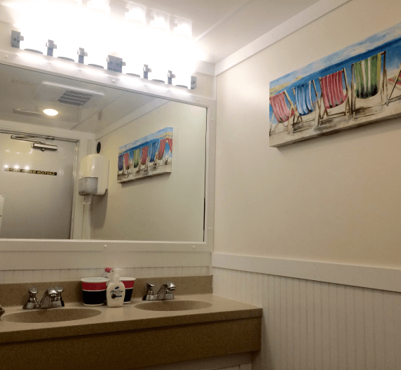 Bathroom interior with mirror, sinks, and beach-themed artwork on the wall.